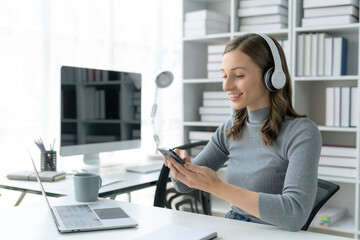 Woman wearing headphones and using a phone enjoying listening to music.