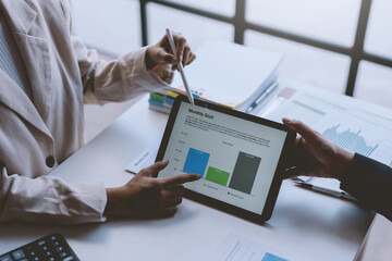 Business people using tablet presents business graph data at a meeting.