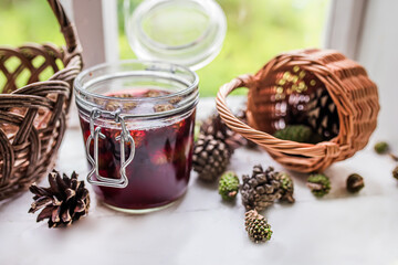 Delicious pine cone jam, a unique and healthy culinary delight made by hand from natural gifts on the windowsill of a herbalist. Basket with green pine cones
