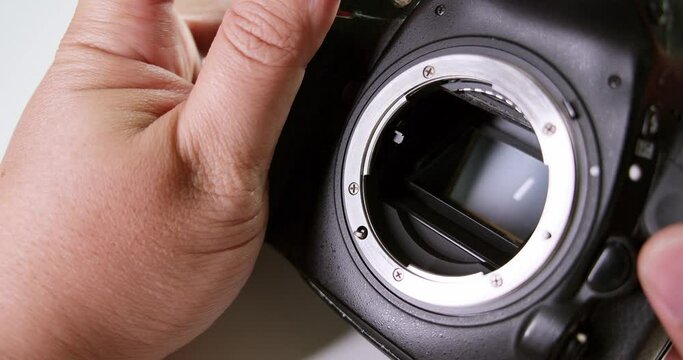 Close-up of a technician clicking the shutter and meticulously checking the sensor of a DSLR camera.