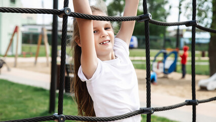 Happy child climbing the net in the playground