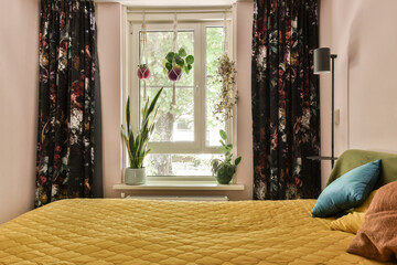 a bed with yellow comforter and pillows in front of a large window that looks out to the garden...