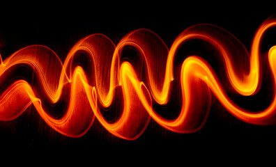 Light wave trail path, vibrant neon gold color in abstract swirls on a black background.