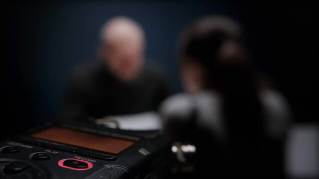 Digital voice audio dictophone, blinking REC button, closeup. Female detective interrogates suspected criminal. Police officer or FBI agent asks arrested mafia to sign papers without a lawyer