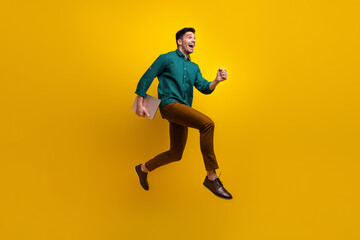 Photo of positive glad man wear trendy clothes running empty space hurrying black friday offer isolated on yellow color background