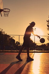 Man playing basketball on a public court in golden hour time.