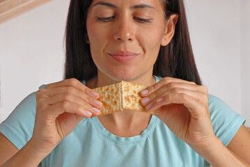 Young woman breaking half cracker soda in the kitchen.