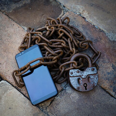 An iron chain with a lock binds the smartphone. The concept of cell phone addiction.