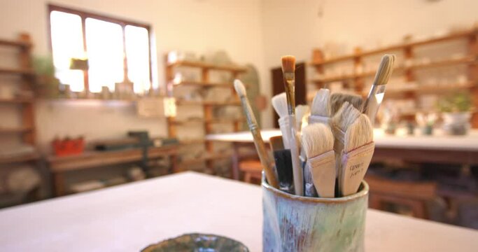 Brushes and pottery tools on desk in pottery studio