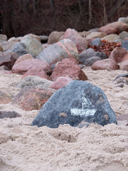Sailboad drwan at the stone bi child lying on the beach.