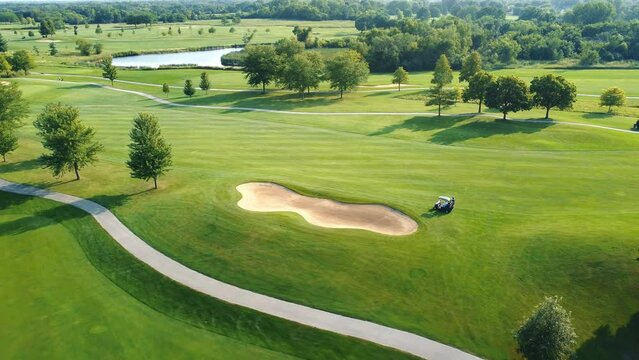 Aerial view of a Golf course. A large green lawn with infrastructure for playing golf. Players in golf cars.