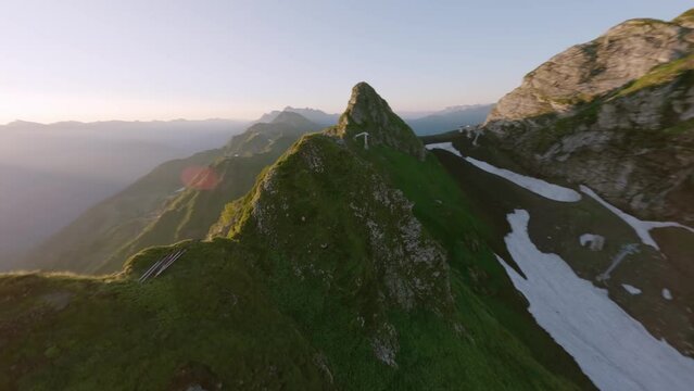 Aerial panorama view sunny mountain range valley running alpine goat wild animal in morning sun. FPV sport drone shot picturesque geology formation landscape industrial tube gazex majestic scenery 4k