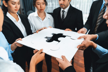 Multiethnic business people holding jigsaw pieces and merge them together as effective solution...