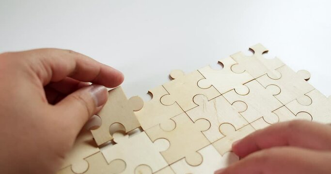 Arranging the pieces of a jigsaw puzzle one-by-one on a table.