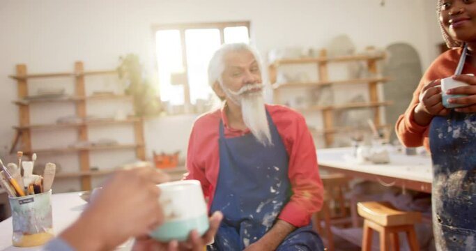 Happy diverse group of potters having break and discussing in pottery studio
