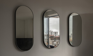 View of Three Capsula pill shaped mirror on white wall with reflecting of Running shoes hung to dry on the balcony. Space for text, Selective focus.