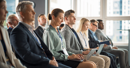 Senior Caucasian Woman Sitting in Crowded Audience at Business Conference. Female Top Manager Smiling, Using Laptop Computer. Specialist Watching Presentation About Investing In Innovative Startups.