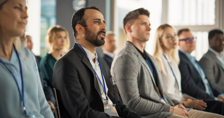 Multiethnic Male Technology Conference Attendee Sittign In Crowd And Listening to Presentation Of Innovative Gadget. Middle Eastern Man Looking For Investment Opportunities At International Tech Forum
