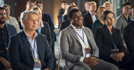 Diverse Business People Sitting In Audience At International Technology Conference. Male And Female Entrepreneurs Listening To Keynote By Startup Company With Innovative Product Or Service.