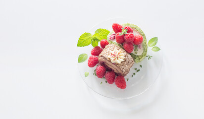 chocolate roll with raspberries and mint leaves on glass plate on  white table