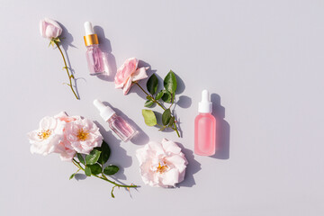 Three different cosmetic bottles with a dropper with oil and a product based on rose petal oil on a...