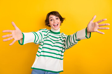 Photo of funny excited lady wear striped pullover smiling open arms ready hug you isolated yellow...