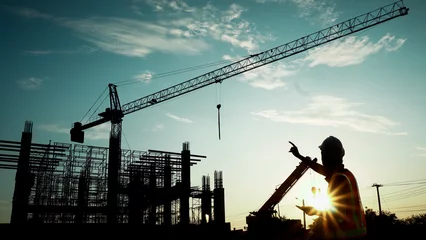 Poster Silhouette of engineer using laptop to control work, crane, construction site © bird_saranyoo