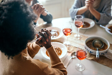 Family and religious concept. Group of multiethnic people with food praying before meal