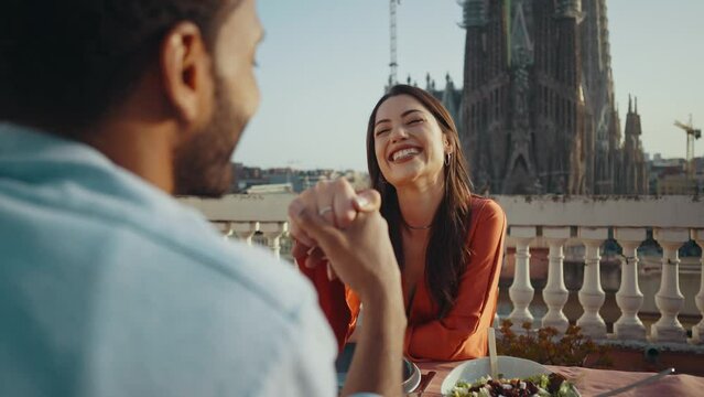 Young multiethnic couple dating for a romantic dinner on a beautiful terrace penthouse in Barcelona