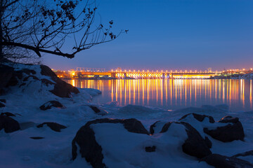 Evening view of DneproGES dam from icy shore of Khortytsia island in winter, Zaporizhzhia, Ukraine