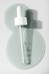 Liquid pipette serum gray gel on light berry colored mirror background