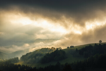 Autumn misty mountainous landscape with morning sun rays shining through the clouds. The Orava...