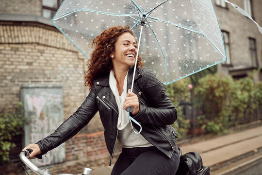 Woman riding her bicycle and laughing on a rainy day