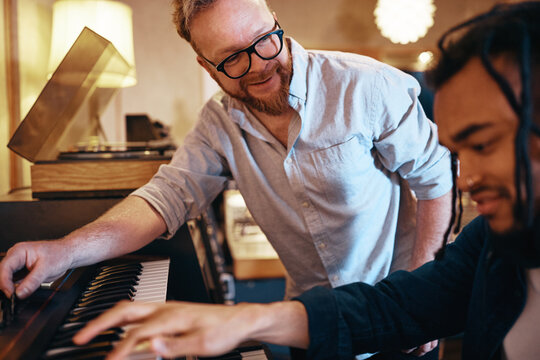 Smiling producer working with a keyboard player in his studio