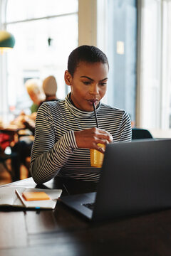 Young female entrepreneur drinking juice while working in a cafe