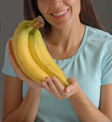 Happy young woman hold banana fruit bunch at home. - 668078906