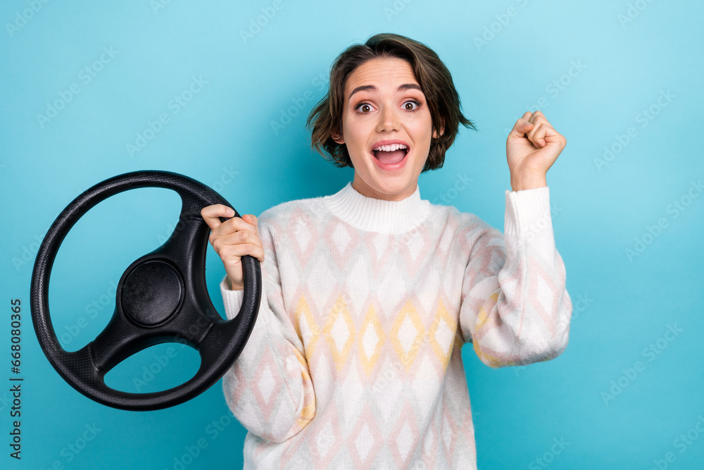 Sticker portrait of delighted cheerful lady arm hold wheel raise fist achievement isolated on blue color bac