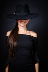 Fototapeta na wymiar Elegant Woman in Black Hat and Off-Shoulder Dress