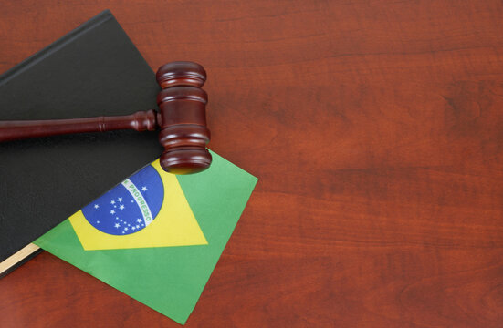 Wooden gavel on legal book with flag of Brazil on table. Copy space for text.