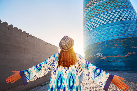 Tourist woman in ethnic dress near Kalta Minar in Ichan Kala of Khiva