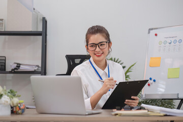 Businesswoman is doing a video conference and showing charts on a clipboard while working at home.