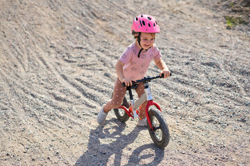 3 years old girl with helmets practicing balance bike, little girl have fun at the pump track, kids with outdoor sports