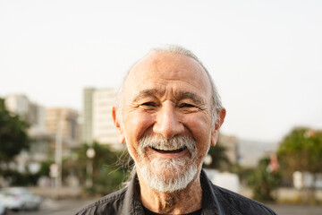Happy senior man smiling in front of camera in the city - Elderly people lifestyle concept
