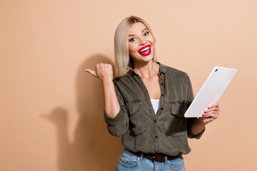 Naklejka premium Photo of shiny impressed woman dressed khaki shirt chatting modern device thumb empty space isolated beige color background