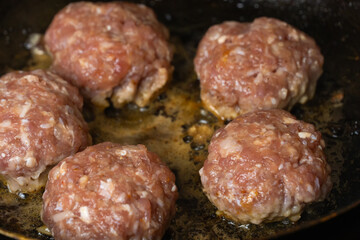 Close-up of minced meat in the form of cutlets is fried in a frying pan. Russian or Polish version of cutlets - kotlety.