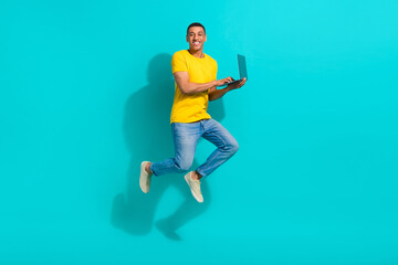 Full size photo of cheerful energetic person jumping hold use wireless netbook isolated on teal color background