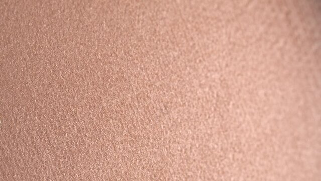 Professional shiny beige eyeshadow, macro. Professional bronzer or highlighter texture, make-up  background, close-up, rotation. Bright brown eye shadows. Cosmetics backdrop. 4K