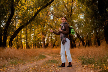 woman walking in the forest, female traveler walking through the forest on a sunny autumn day, young Caucasian woman hiking, girl with a tourist backpack walking in the forest