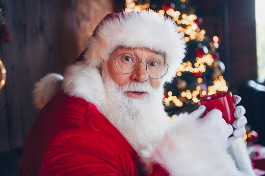 Photo of positive impressed santa claus dressed red eyewear drinking hot tasty eggnog indoors christmas north pole home
