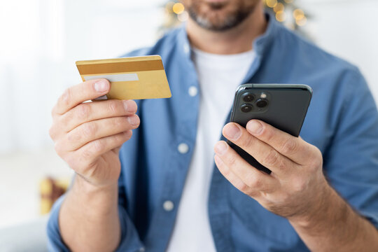 Close-up photo of young male hands holding a credit card and a mobile phone